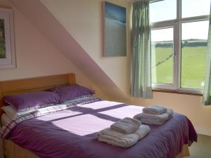 a bedroom with a bed with three towels on it at West Park in Hope-Cove