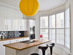 a kitchen with white cabinets and a large yellow light fixture at The Town House in Scarborough