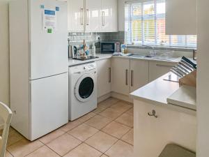 a kitchen with a white refrigerator and a dishwasher at September Cottage in Brancaster