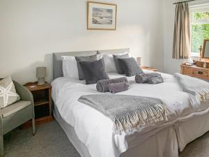 a bedroom with a large white bed with a chair at September Cottage in Brancaster