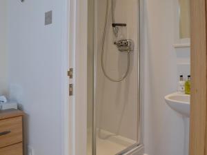 a shower with a glass door next to a sink at September Cottage in Brancaster +9 photos