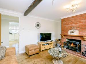 a living room with a fireplace and a tv at Corner House in Cromer