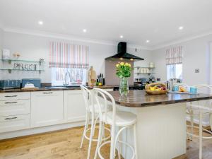 a kitchen with white cabinets and a counter with chairs at Corner House in Cromer +20 photos
