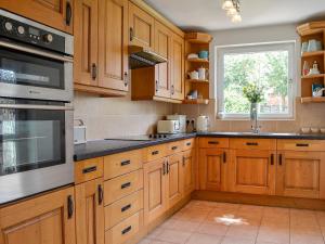 Una cocina con armarios de madera y una ventana. en Applegarth, en Cockermouth