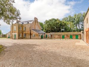 an old brick building with green doors on a gravel driveway at Lode Hall in Upwell