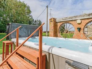 a hot tub on a deck with a brick building at Lode Hall in Upwell