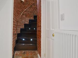 a stairway with a brick wall and black stairs at The Mistress' House in Hunstanton