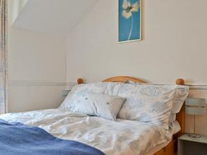 ein ungemachtes Bett in einem Schlafzimmer mit einer blauen Decke in der Unterkunft Beech Cottage in Whitwell