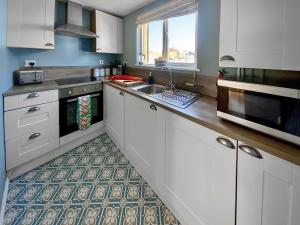 a kitchen with white cabinets and a sink at Corner View in Broadstairs