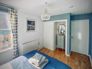 a bedroom with a blue bed and a mirror at Corner View in Broadstairs