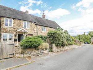 una vecchia casa in pietra con un muro di pietra di Clematis Cottage a Belper