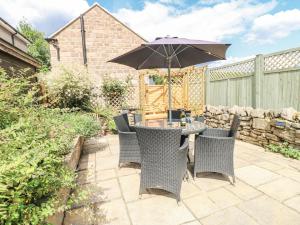 een tafel en stoelen met een parasol op een terras bij Clematis Cottage in Belper