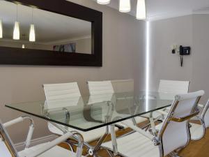 a glass dining room table with white chairs and a mirror at Hollies Cottage 10- Ukc4536 in Martock