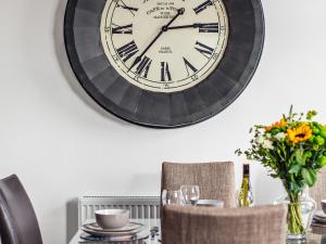 a large clock hanging on a wall above a table at Dyma Y Bywyd in Tenby