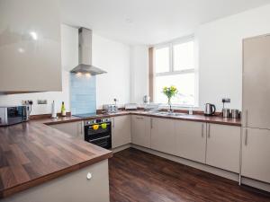 a kitchen with white cabinets and a wooden floor at Dyma Y Bywyd in Tenby