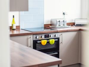 a kitchen with a stove with yellow mugs on it at Dyma Y Bywyd in Tenby