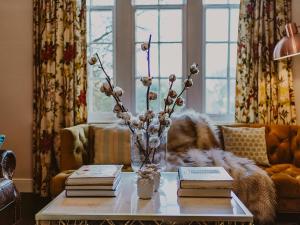 a living room with a vase of flowers and books on a table at Rose Blair Lodge - Uk31045 in Portpatrick