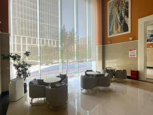 a lobby with tables and chairs and a large window at Magnificent International Hotel in Shanghai