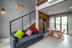 a living room with a blue couch with colorful pillows at Nusa Djiwa in Tanah Lot
