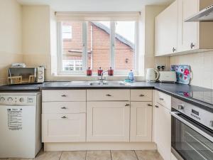 a kitchen with white cabinets and a sink and a window at Country View - Uk38223 in Ashby cum Fenby