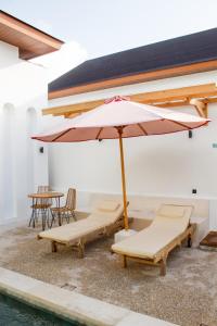 a pool with two lounge chairs and an umbrella at Jaya Villas #1 in Uluwatu +53 photos