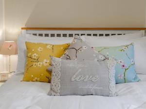 un letto con cuscini e un cuscino che dice amore di Partridge Cottage a Kirk Leavington