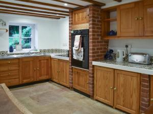 une cuisine avec des placards en bois et un mur en briques dans l'établissement Keeper's Cottage, à Crowborough