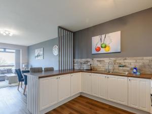 a kitchen with white cabinets and a living room at Cottage 7 - Uk38218 in Ashby cum Fenby