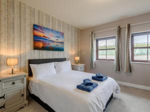a bedroom with a large white bed with two windows at Cottage 7 - Uk38218 in Ashby cum Fenby +8 photos