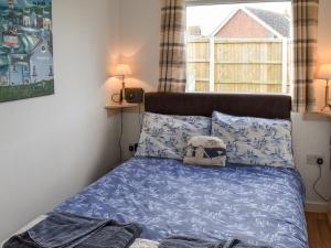 a bedroom with a bed with blue sheets and a window at On The Beach in Bacton
