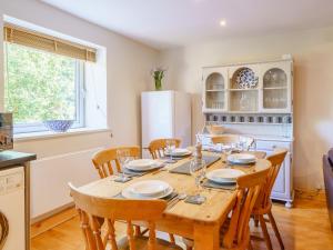 a kitchen with a table with chairs and a refrigerator at 1, The Barns in Threlkeld