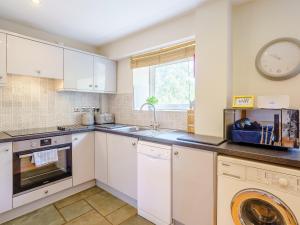 a kitchen with white cabinets and a clock on the wall at 1, The Barns in Threlkeld