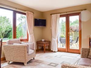 a living room with chairs and a tv and sliding glass doors at Sheildaig Cottage Annex in Laurencekirk