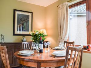 a dining room with a wooden table and a window at Sheildaig Cottage Annex in Laurencekirk