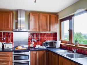 a kitchen with wooden cabinets and a sink and a window at Sheildaig Cottage Annex in Laurencekirk +10 photos