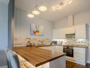 a kitchen with white cabinets and a wooden counter top at Cottage 8 - Uk38219 in Ashby cum Fenby