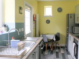 eine Küche mit Spüle und Tisch mit Stühlen in der Unterkunft Riversdale Cottage in Saint Fillans