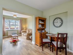 a living room with a table and a clock on the wall at Potting Shed - Uk48564 