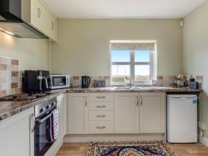 a kitchen with white cabinets and a sink and a window at Potting Shed - Uk48564  +6 photos