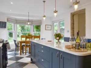 a kitchen with blue cabinets and a table with wine glasses at Brookleigh Farm Cottage in Burley in Wharfedale