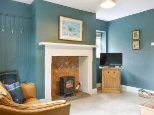 a living room with a fireplace and a tv at Brookleigh Farm Cottage in Burley in Wharfedale