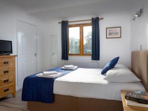 a bedroom with a bed and a window and a television at Mallard in Wroxham