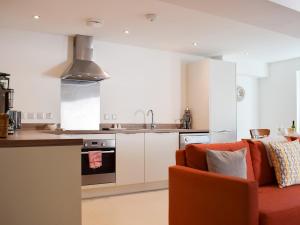 a kitchen with an orange couch in a room at Potters Pad in Alnwick