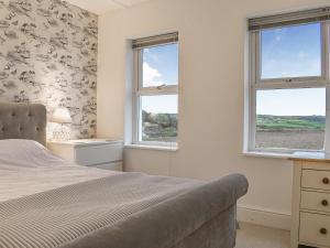 a bedroom with two windows and a bed at Greenacres in Saint Ervan