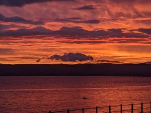 a sunset over a body of water with a fence at Strathclyde Cottage North in Skelmorlie +2 photos