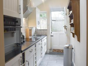 a kitchen with white cabinets and a window and a door at Lantern Cottage in Lyndhurst