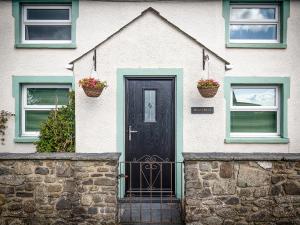 a white house with a black door and two windows at Bryn Olwyn in Little Newcastle