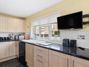a kitchen with a sink and a tv on the wall at Bryn Olwyn in Little Newcastle +32 photos