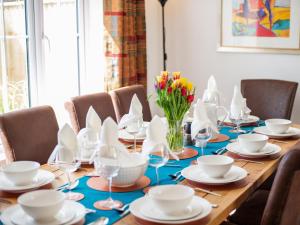 Una mesa larga con platos y tazas y un jarrón de flores. en Oakwood, en Everton