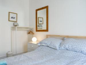 ein Bett mit einer blauen Bettdecke und einem Spiegel in der Unterkunft Berkeley Cottage in Ilfracombe + 7 Fotos
